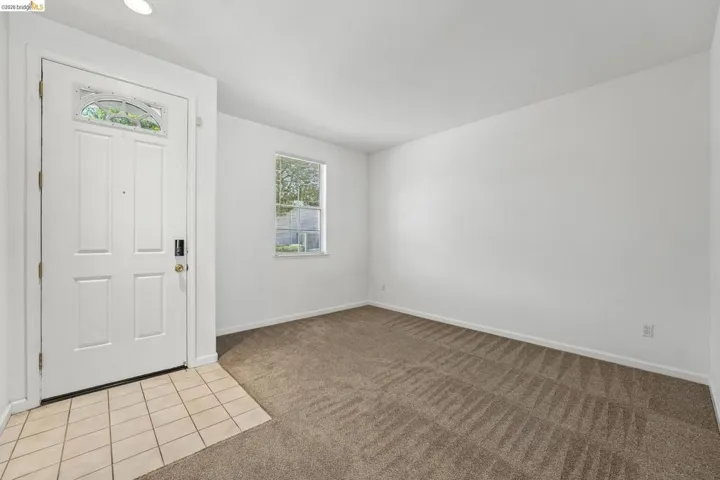 Entryway featuring a paneled door with decorative glass insert, recessed lighting, and a neutral tile floor