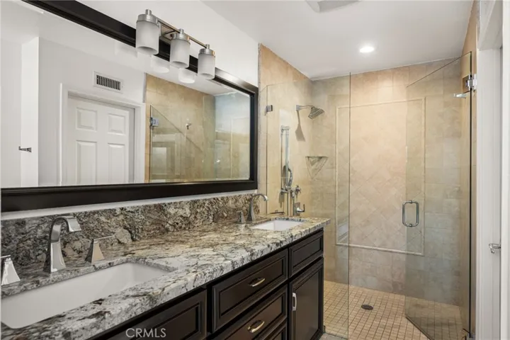 Remodeled primary bathroom with dual sinks & walk-in shower.