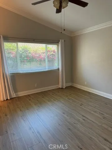 Primary Bedroom Laminate Flooring, crown molding and ceiling fan