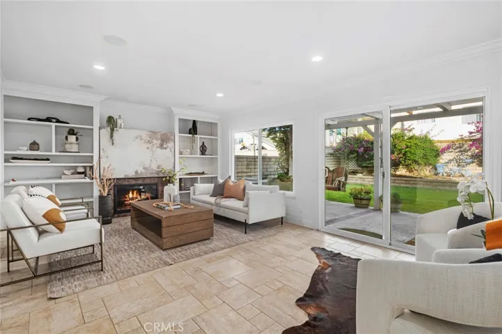 Elegant travertine flooring, crown molding, plantation shutters, recessed lighting, and built-in  create a warm, sophisticated atmosphere