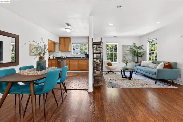 Open-concept living area featuring wood-finish flooring, recessed lighting, and bright white walls