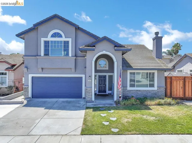 Two-story stucco home featuring a prominent arched entryway and a two-car garage