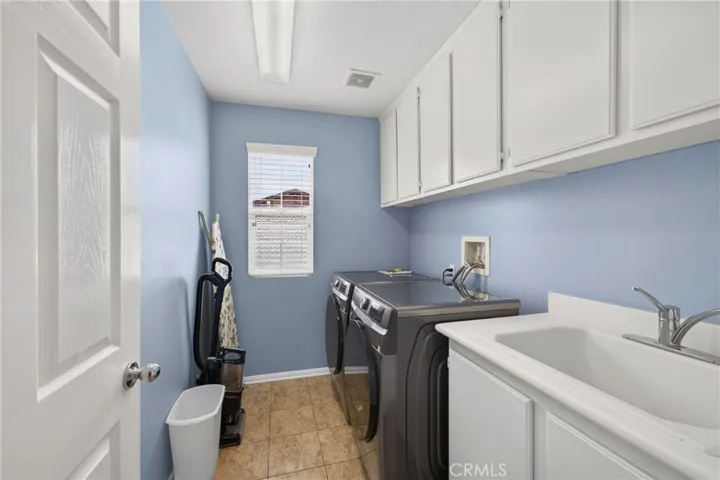 Upstairs laundry room with cabinets and utility sink