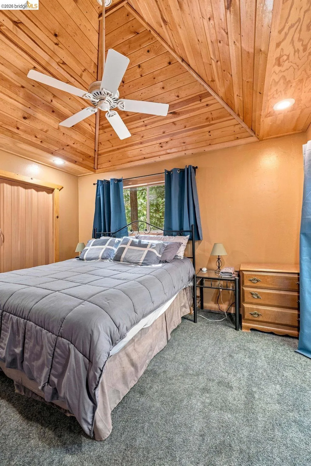 Vaulted wood-paneled ceiling with a central ceiling fan