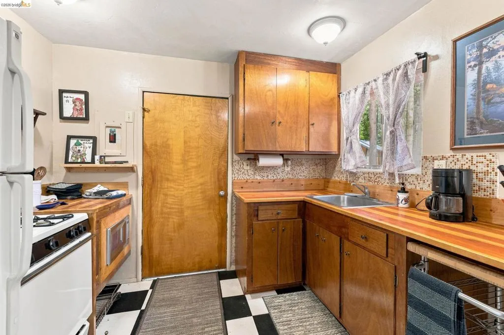 Compact kitchen featuring wood cabinetry and wood-finish countertops