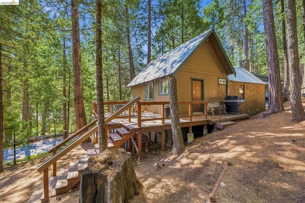 A-frame style residence featuring a prominent front deck with stairway access, a metal roof, and vertical siding