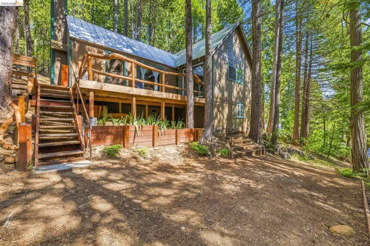 Wood-sided residence with multiple outdoor living areas, including a ground-level deck and an elevated balcony