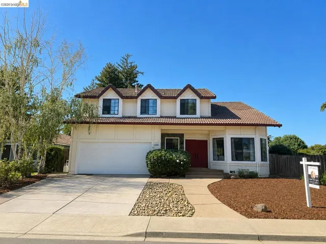 Two-story stucco residence featuring a tile roof, three dormer windows, and a two-car garage