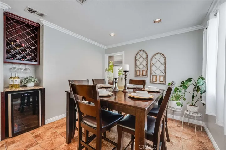 Stylish Dining Room Area with Built-In Cabinets, Granite Counter tops, Wine Refrigerator, Tiled Floors and Crown Molding