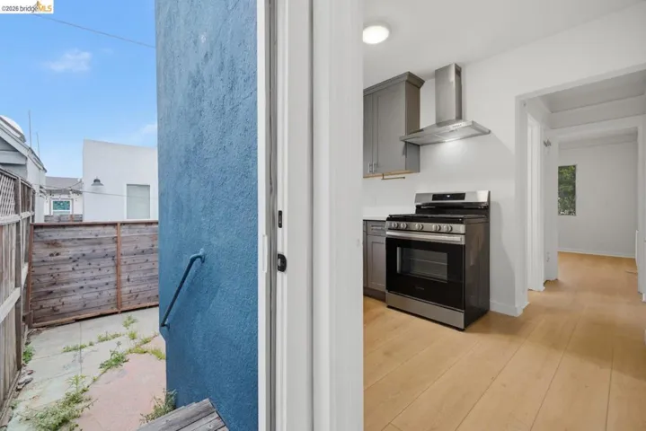 Modern kitchen featuring stainless steel appliances, grey cabinetry, white countertops, and wood-finish flooring