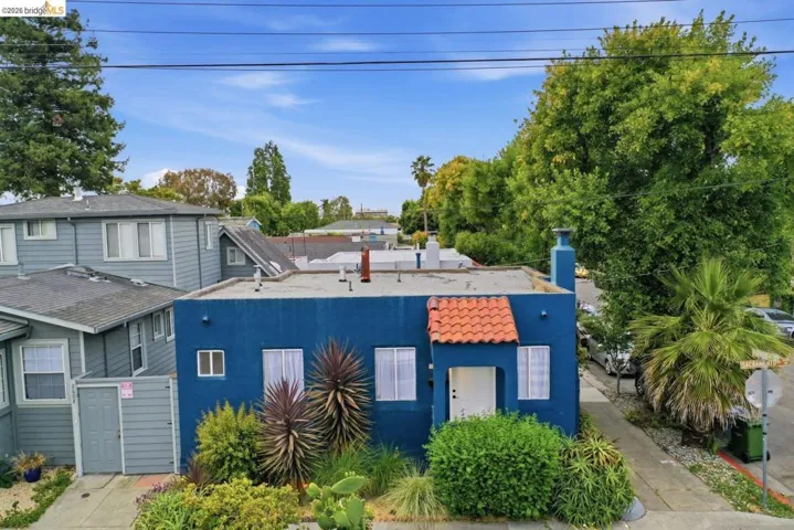 Blue stucco exterior with a flat roof and terracotta-tiled entryway awning