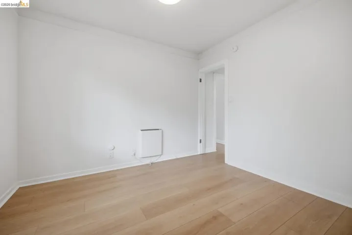 Room featuring wood-finish flooring, white walls, and white baseboards