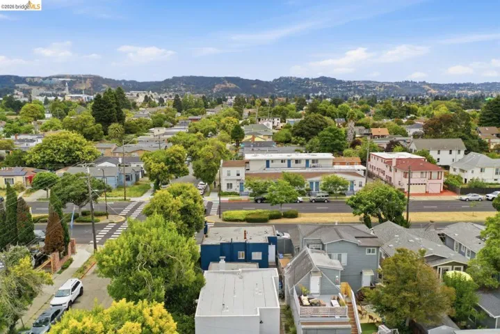 Expansive residential neighborhood featuring mature trees, diverse architectural styles, and distant hillside scenery