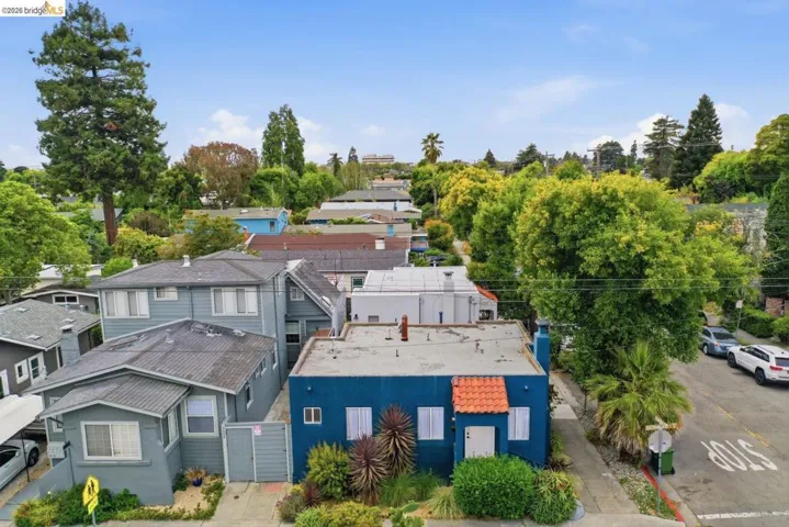 Blue exterior with a red tile accent roof, street-facing entrance, and mature landscaping