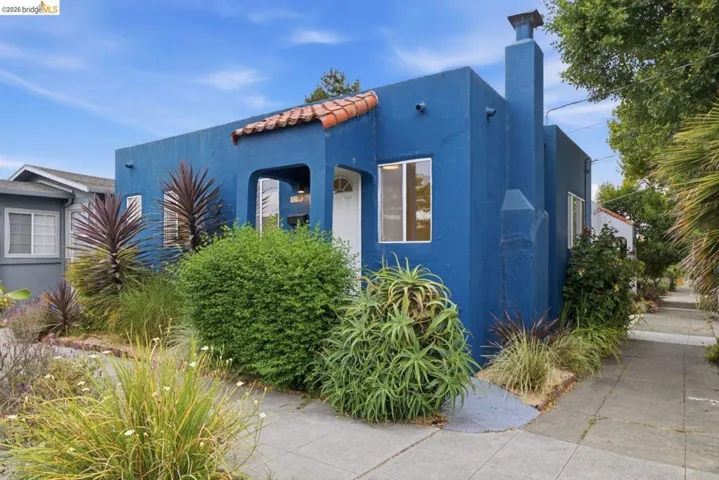 Stucco exterior featuring a prominent chimney, terracotta tile roof accent, and an arched entry