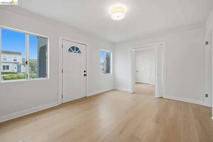 Bright interior space featuring light wood-finish flooring, white walls, and white trim
