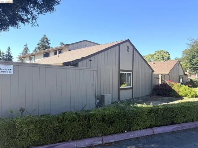 Exterior property featuring a neutral-toned vertical siding, brown trim, and a gabled roofline