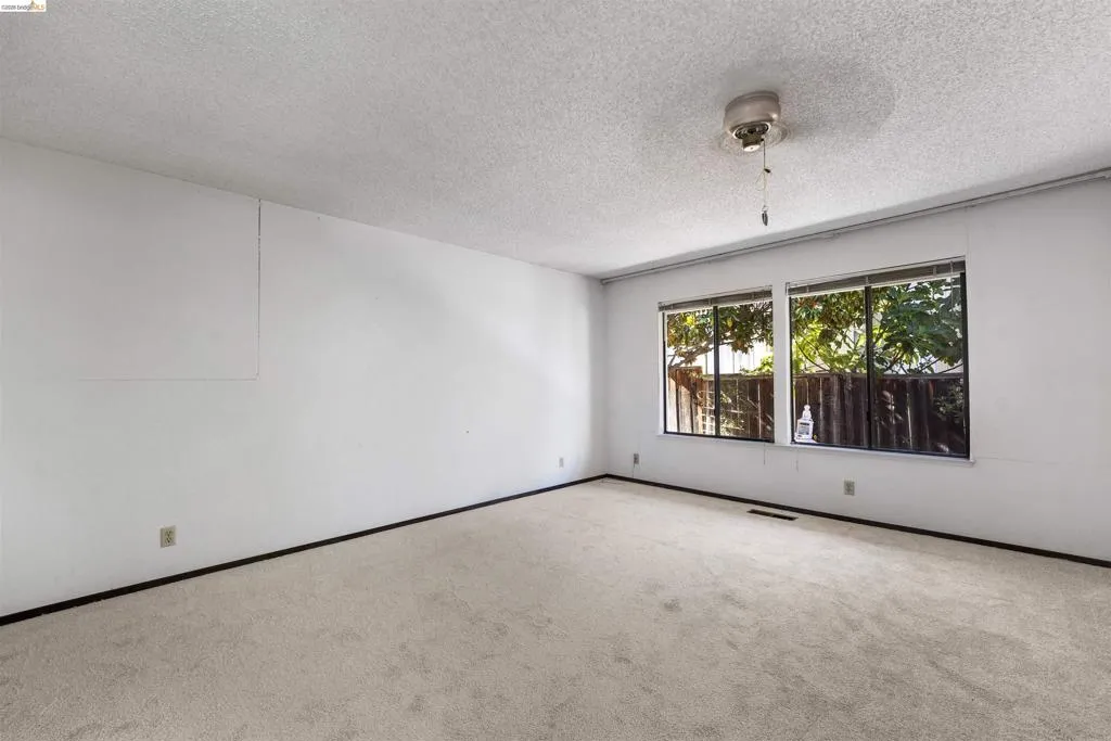 Spacious room featuring light-colored carpeting, white walls, and a textured ceiling Spacious room featuring light-colored carpeting, white walls, and a textured ceiling