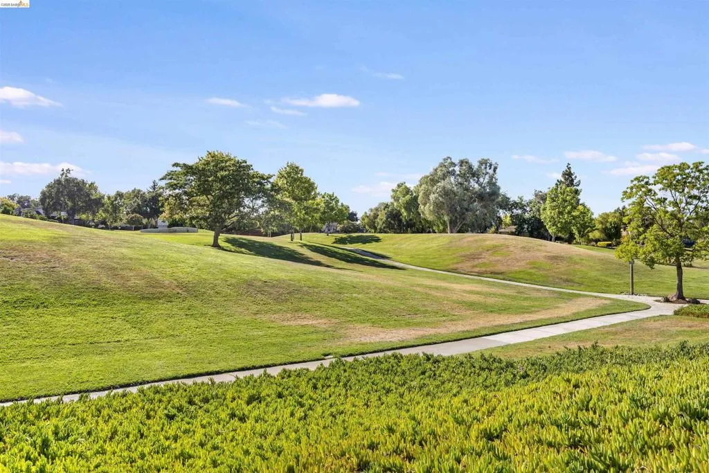 Expansive green space featuring rolling hills and a paved walking path Expansive green space featuring rolling hills and a paved walking path