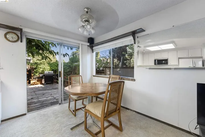 Dining area with beige carpeting, a ceiling fan, and sliding glass doors opening to an outdoor deck