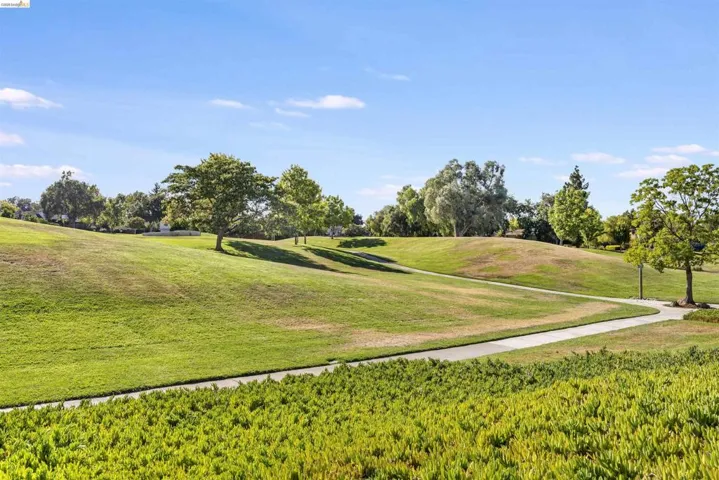 Expansive green space featuring rolling hills and a paved walking path