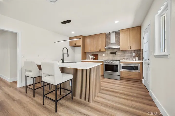 Beautifully redesigned kitchen with gold and white quartz countertops, wood shaker cabinetry, and a large center island with decorative wood accents
