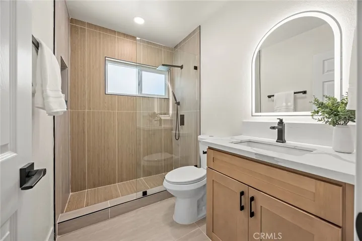 Updated hallway bath with large-format porcelain tile, marble shower flooring, and a new vanity