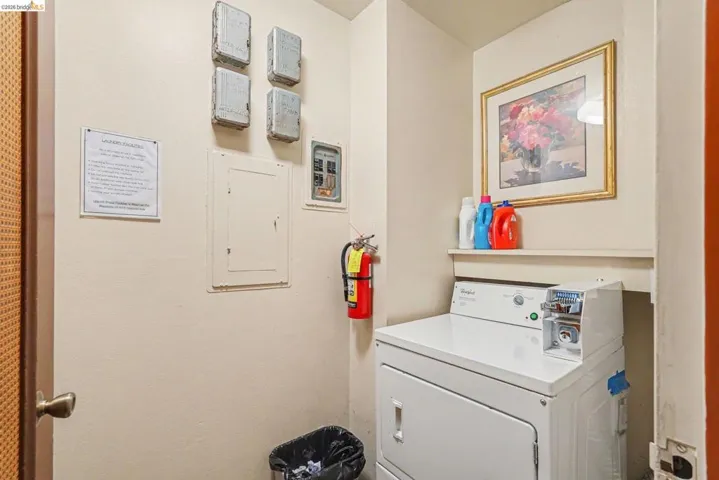Dedicated laundry area featuring a white top-load washing machine, a built-in wall shelf, and a framed floral art piece