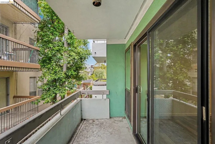 Private balcony featuring a concrete floor, painted railing, and green wall accent