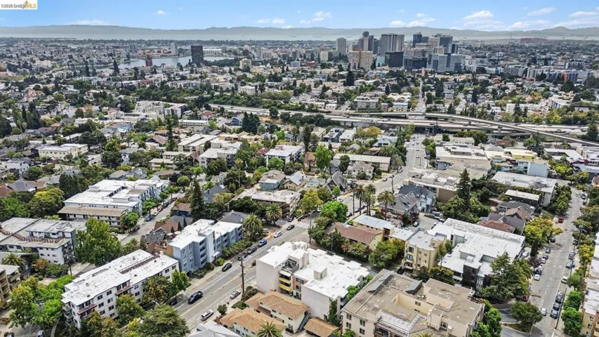 Urban landscape featuring a diverse architectural mix, extensive green spaces, a prominent downtown skyline, a visible body of water, and surrounding hills