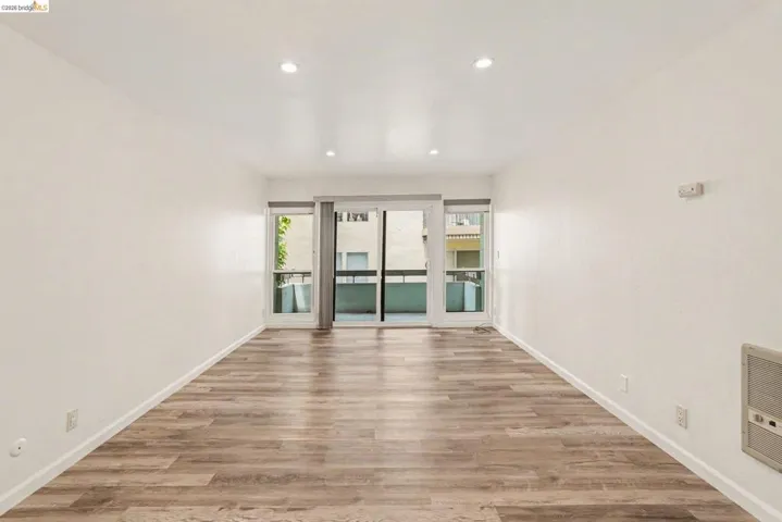Spacious room featuring wood-finish flooring, white walls, and recessed lighting