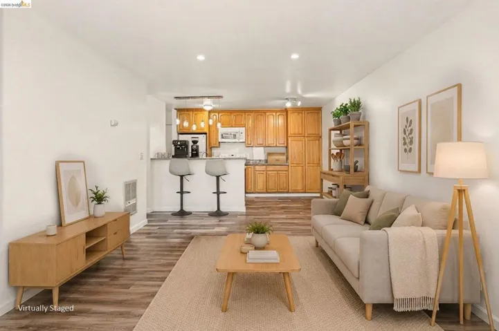 Open-concept living area featuring wood-finish flooring, recessed lighting, and a breakfast bar