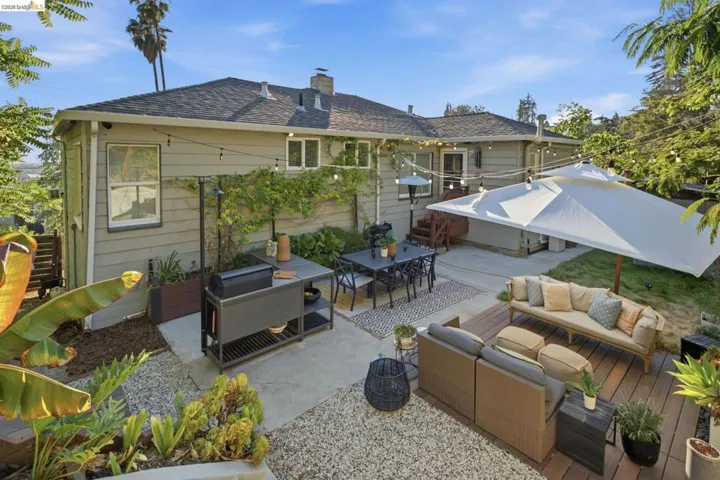 Expansive outdoor patio featuring concrete and gravel areas, a dedicated decking space, and lush perimeter landscaping