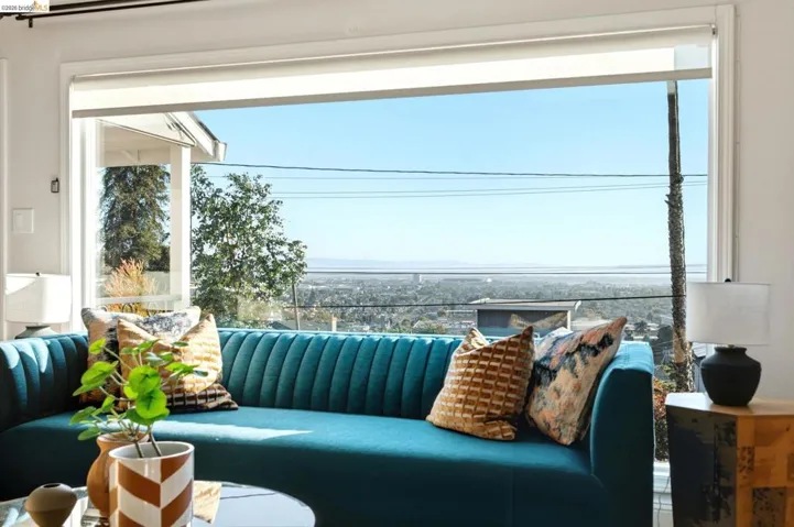 Expansive floor-to-ceiling window showcasing distant city and bay scenery. Hunter Douglas Electric Blinds