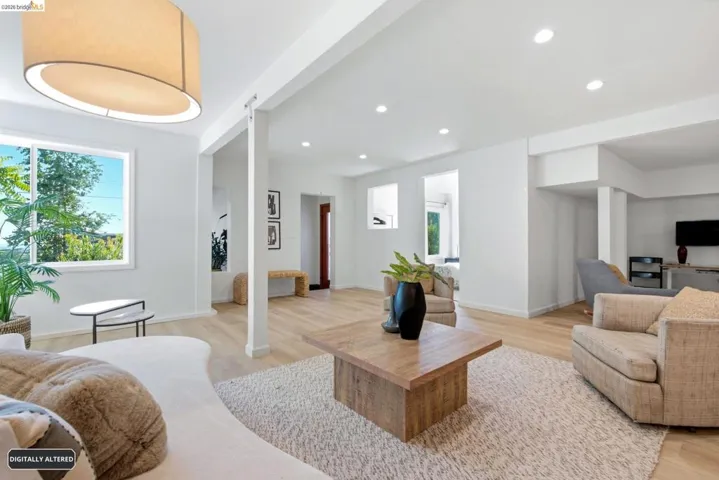 Spacious interior with light wood-finish flooring, recessed lighting, and a drum pendant light fixture