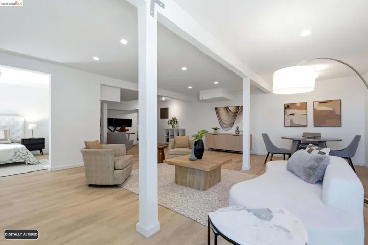 Open concept living area with light wood-finish flooring, recessed lighting, and white support columns