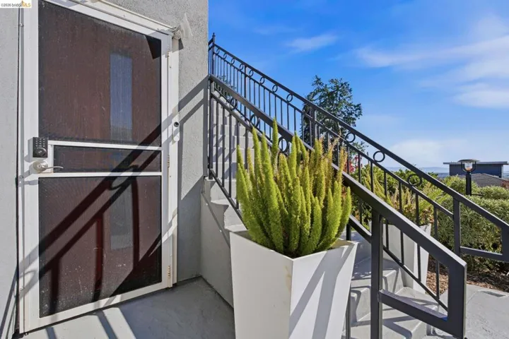 Exterior entry featuring a screen door with a keyless entry pad, concrete steps, and a wrought iron handrail