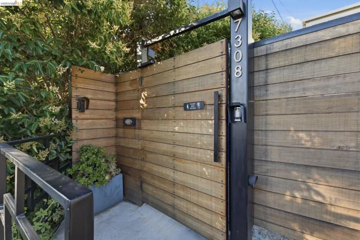 Wood-slat privacy gate with a black metal frame and handle