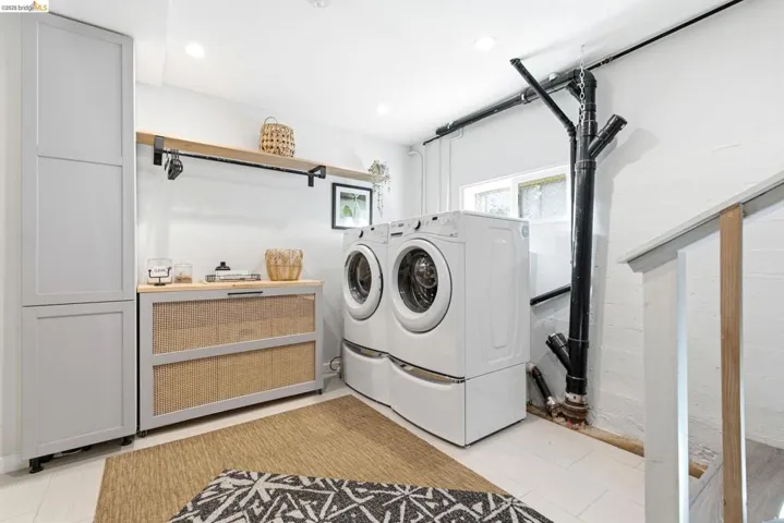 Dedicated laundry area featuring appliances, a tall storage cabinet, a wood-finish shelf, and a built-in hamper with a wood-finish top