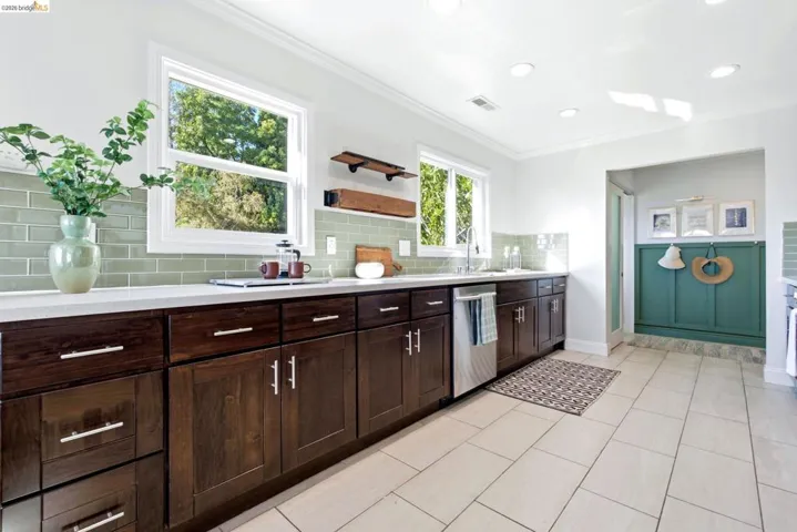 Contemporary kitchen featuring dark wood cabinetry, light-colored countertops, and a subway tile backsplash
