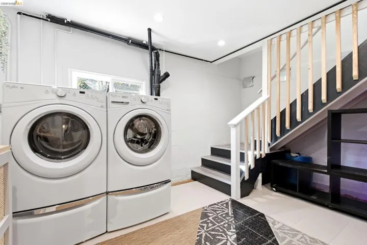 Dedicated laundry area featuring front-loading washer and dryer unit. Stairway leads to upper floor
