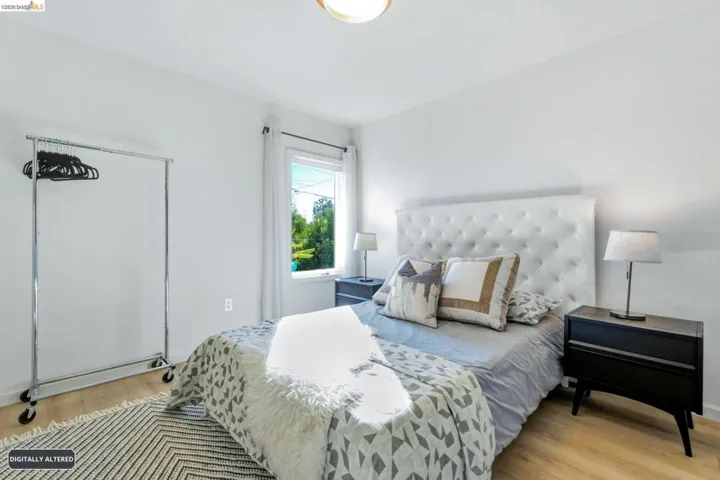 Bright bedroom featuring light wood-finish flooring, white walls, and a recessed window