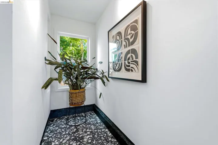 Windowed alcove featuring white walls, a black and white speckled floor, and dark trim