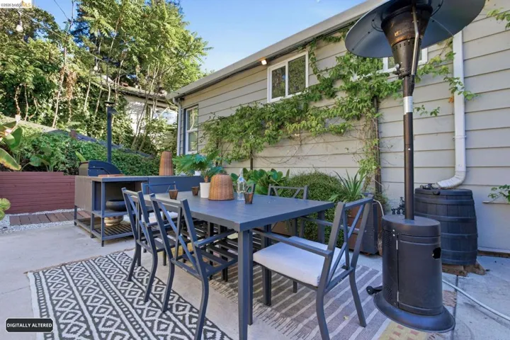 Outdoor patio area featuring a dining set, an outdoor kitchen with a built-in grill, and mature landscaping