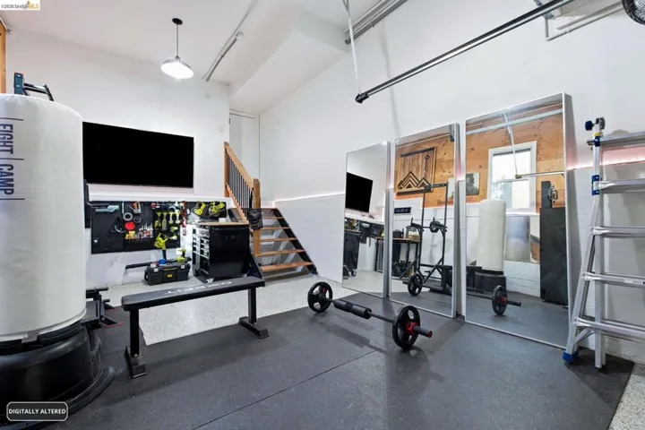 Versatile space featuring a rubberized floor surface, a built-in staircase with a wood railing, recessed ceiling lighting, and a wall-mounted organizational system