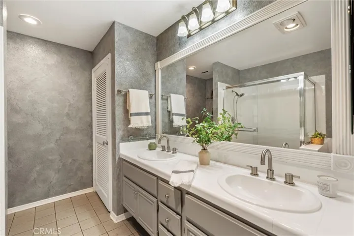 Primary bathroom with dual vanities, bathtub and shower enclosure