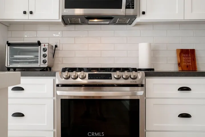 Close up view of gas range, oven subway tile backsplash, soft closing cabinets and drawers.