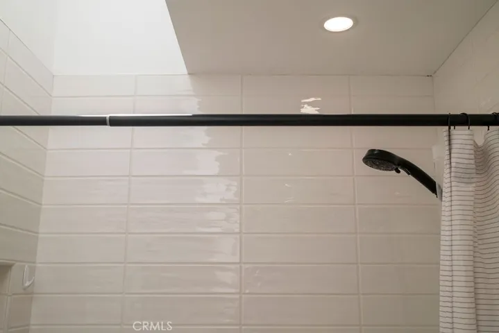 Close-up of updated tile surround, downlighting, and vaulted skylight in upstairs bathroom.