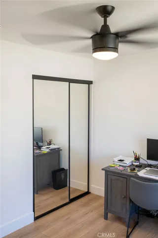 Secondary bedroom view showing mirrored wardrobe doors and ceiling fan.