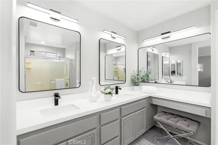 L shape dual vanities with quartz countertops, framed mirrors and new lighting